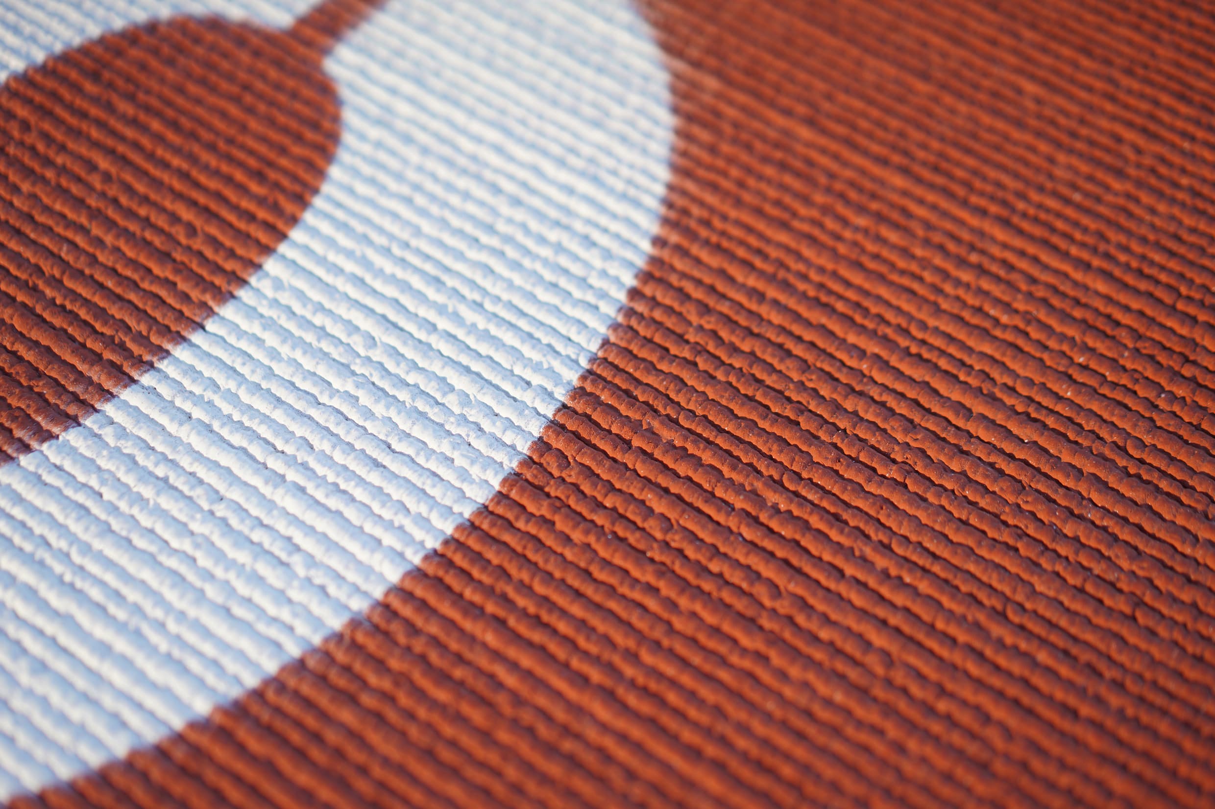 Close-up of the prefabricated track surface, showing the fine ribbed texture running across the red rubber and a white lane line crossing it.